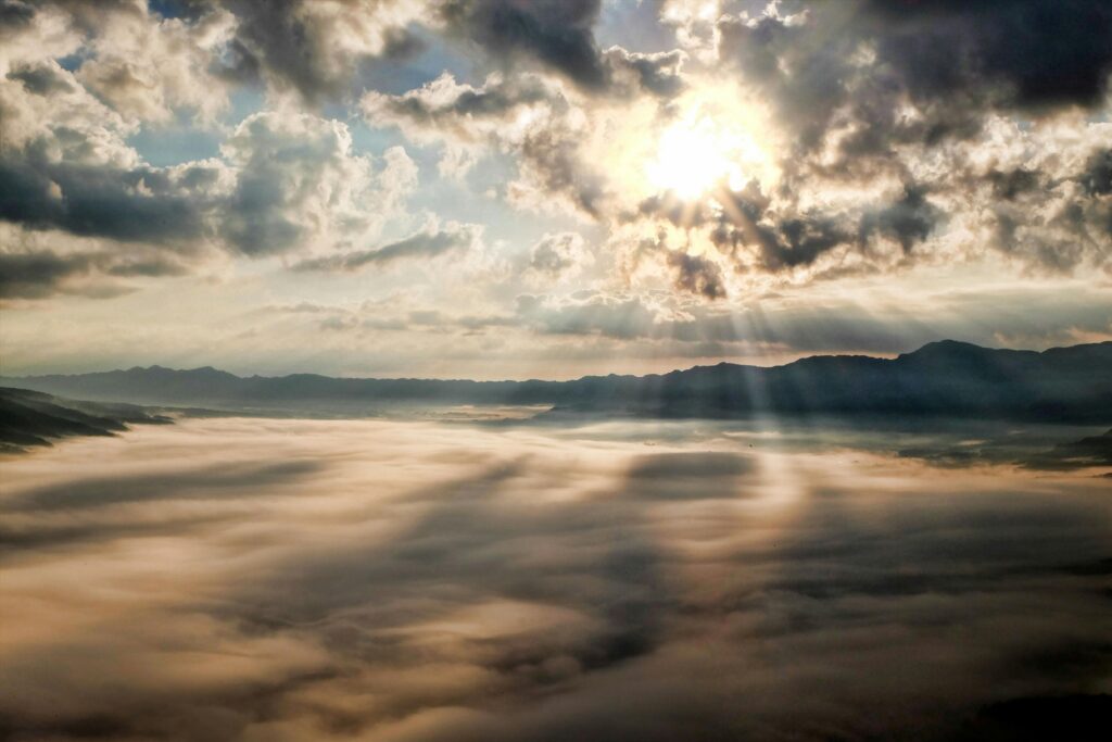 kumamoto-japan-aso-cloud-45848-45848 Captivating view of the sun breaking through clouds over a mist-covered mountain range.